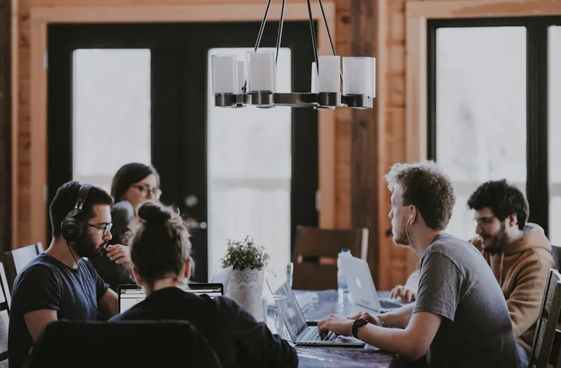 A small team working together around a table of laptops